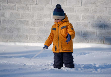 cute European boy with big icicle on a walk on a Sunny winter dayの写真素材