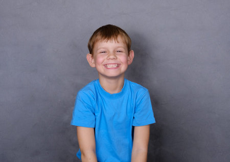 cute European boy laughs heartily . gray background
