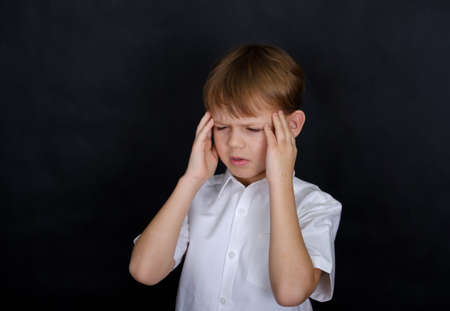 boy European appearance holding his head in pain. headache concept. isolate on a black backgroundの写真素材