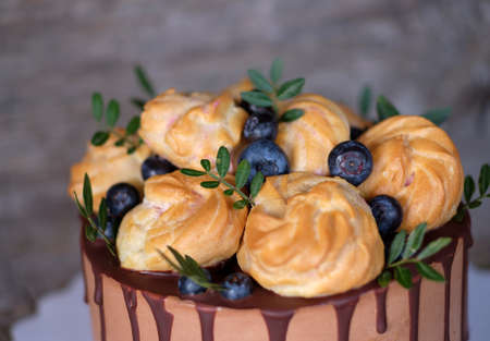 Beautiful homemade cake with profiteroles and blueberries on a wooden tableの写真素材
