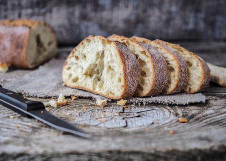 appetizing sliced ciabatta bread with olives on a wooden tableの写真素材
