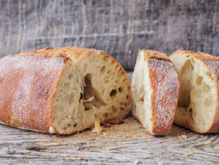 appetizing sliced ciabatta bread with olives on a wooden tableの写真素材