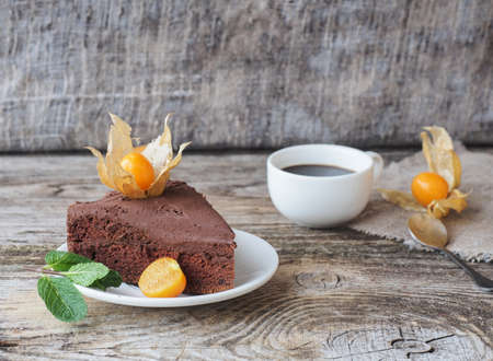 homemade sponge cake with chocolate-coconut cream and physalis on a wooden tableの写真素材