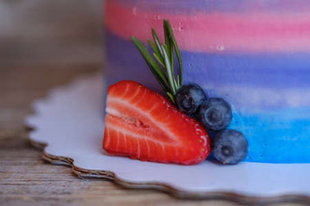 beautiful home made cake with cottage cheese cream, decorated with strawberries, blueberries and coconut on wooden tableの写真素材