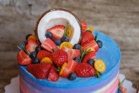 beautiful home made cake with cottage cheese cream, decorated with strawberries, blueberries and coconut on wooden tableの写真素材