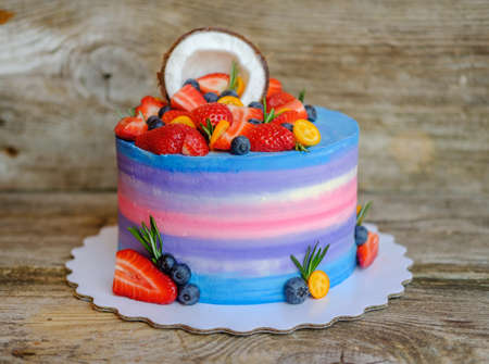 beautiful home made cake with cottage cheese cream, decorated with strawberries, blueberries and coconut on wooden tableの写真素材