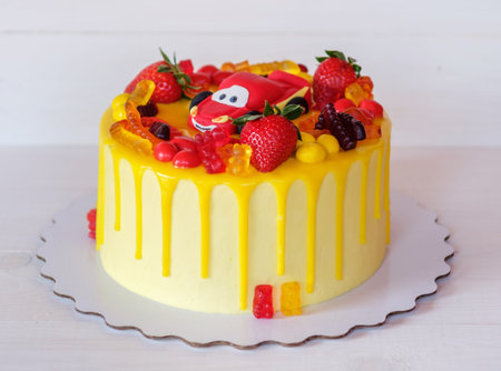 beautiful children's cake with a bright yellow cheese cream, decorated with a red machine,...