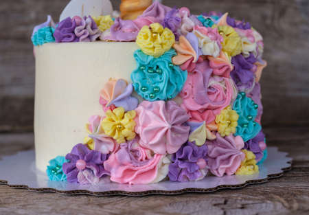 beautiful homemade cake in the form of a unicorn with cream colored flowers on a wooden tableの写真素材