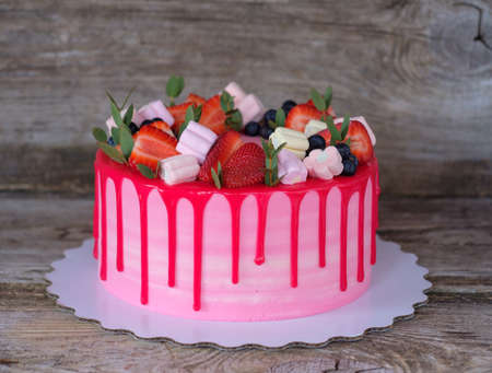 beautiful homemade cake with pink and red cream, decorated with strawberries and marshmallowsの写真素材
