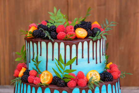beautiful wedding cake in two tiers, decorated with fresh raspberries, blackberries, blueberries, chocolate icingの写真素材