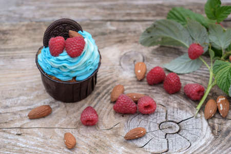 beautiful cupcakes with blue cheese cream decorated with fresh raspberries and almonds on wooden backgroundの写真素材