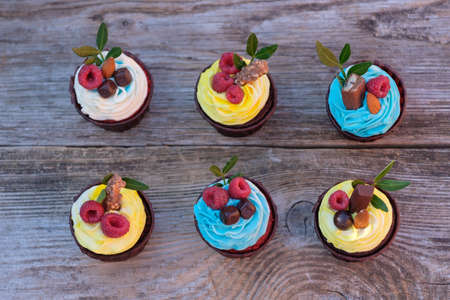 beautiful cupcakes with blue cheese cream decorated with fresh raspberries and almonds on wooden backgroundの写真素材