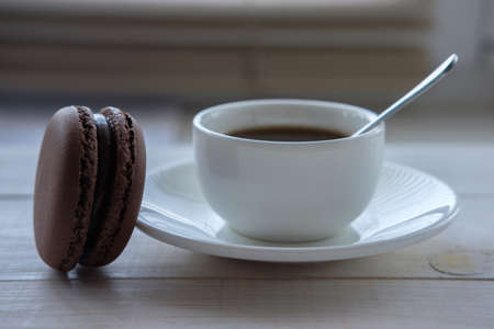 black coffee in white Cup and macaroon cakes on white wooden backgroundの写真素材