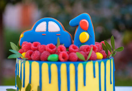 beautiful birthday cake for a child with the number one and the machine, decorated with fresh raspberries and strawberries, with yellow cheese creamの写真素材
