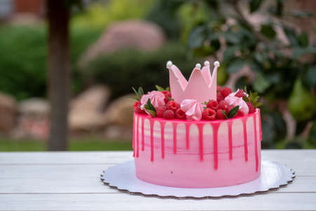 pink birthday cake decorated with Princess crown, raspberry berries and marshmallowの写真素材