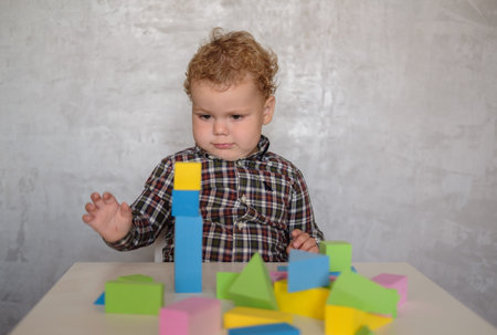 European boy of two years builds a tower of colored blocks