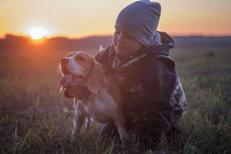 European boy and dog Beagle on a walk in the autumn evening at sunsetの写真素材