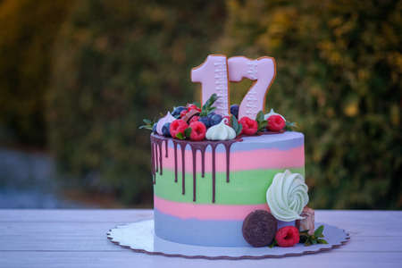 beautiful birthday cake with the number seventeen, decorated with fresh berries and colorful creamの写真素材