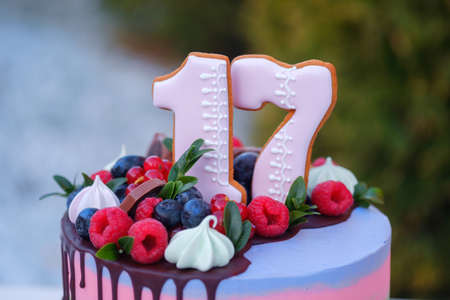 beautiful birthday cake with the number seventeen, decorated with fresh berries and colorful creamの写真素材