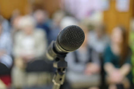 Microphone in concert hall or conference room with defocused bokeh lights in background. Extremely shallow dof. People in blurの写真素材
