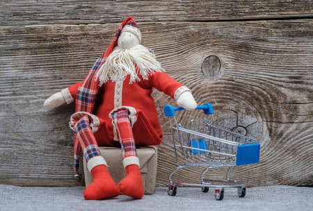 rag doll Santa Claus with a metal trolley supermarket. the concept of purchasing Christmas giftsの写真素材