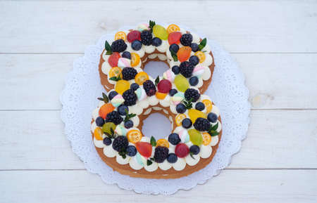 beautiful homemade cake in the shape of number eight with natural berries on white background. cake for international women's day, birthday cake.の写真素材