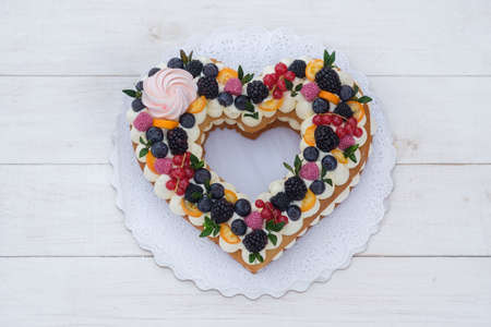 beautiful heart shaped cake with fresh berries for Valentine's day on white wooden backgroundの写真素材