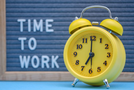 vintage yellow alarm clock at the background of the inscription is the time to work on the English...