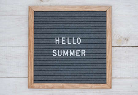 English text Hello summer on a letter Board in white letters on a gray background. letter Board on white wooden backgroundの写真素材