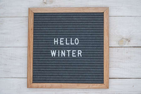 the English text Hello winter in a letter to the Board in white letters on a gray background. letter Board on white wooden backgroundの写真素材