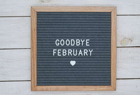 text in English goodbye February and a heart sign on a gray felt Board in a wooden frame. letter Board on white wooden background top viewの写真素材