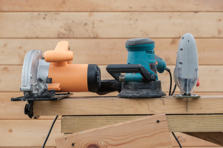 electric building tools for wood work on wooden wall background. circular saw, sander, jig saw