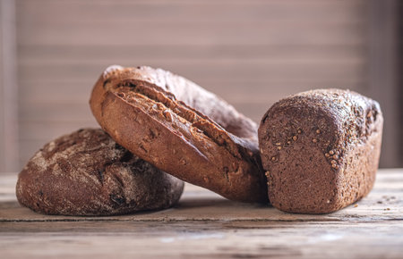 three loaves of rye -wheat bread of round, oval and rectangular shape on a wooden table . home-baked...
