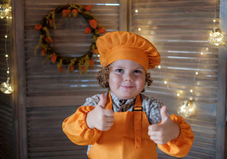 cute funny boy in a chef costume shows a like gesture. little chef in the kitchenの写真素材
