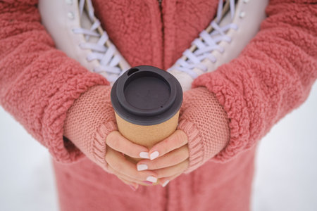 a young woman in a pink eco-fur coat holds white skates on her shoulder. part of the body without a...