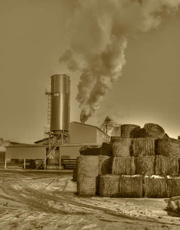 Smoke from rural refinery, sepia colored photoの写真素材