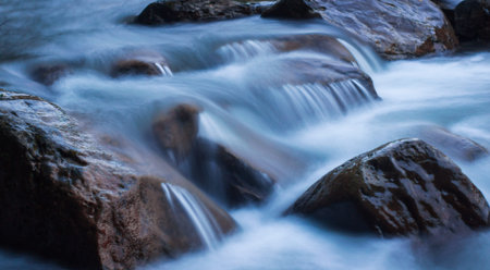Power of water. Nature scene of rough, fast flowing river hitting the stones, making mini...