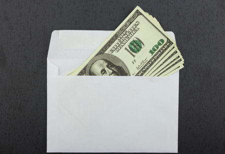 Dollars lie in a white envelope on a black background