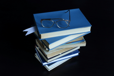 books lie on each other, near reading glasses. dark backgroundの写真素材