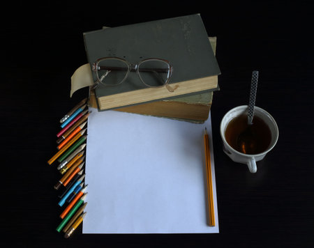 books lie on each other, near reading glasses, pencil. dark background