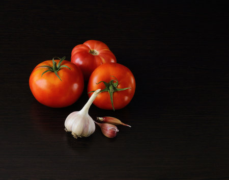 tasty and healthy food for your health bright and tasty tomatoes and pungent garlic on a dark backgroundの写真素材