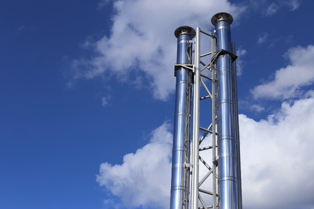 Pipes of shiny metal. Against the background of a high blue sky and cloudsの写真素材