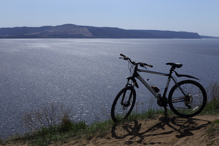 Silhouette of a sport bike against the background of a big river. There are mountains in the distance. Blue sky.の写真素材