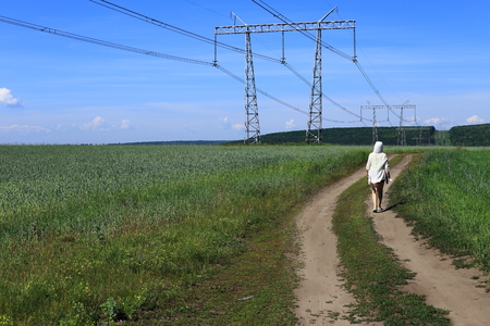 woman in a white sweater. view from the back. goes on the road. summer and green grass.の写真素材