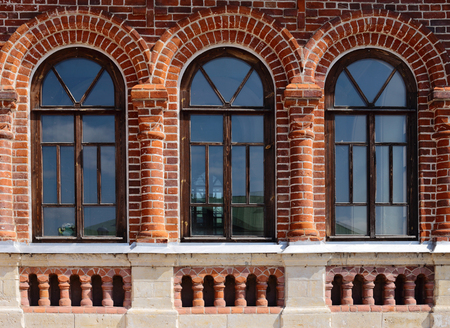 the wall of an old red brick building. There are three windows in the form of an arch.の写真素材