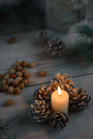 lighted candle, forest cones, hazelnuts on a wooden table,の写真素材