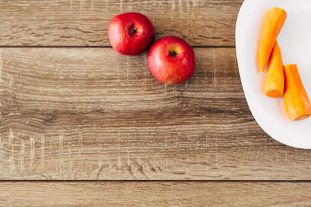 red apple and yellow carrots on the wooden table, live food, helpfulの写真素材