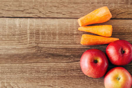 red apple and yellow carrots on the wooden table, live food, helpfulの写真素材