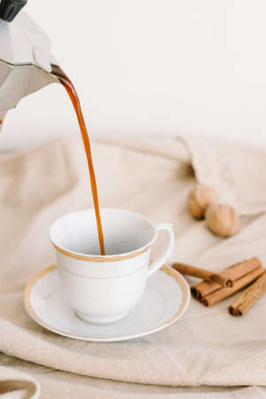 hot black coffee in a white cup on a napkin beige, cinnamonの写真素材