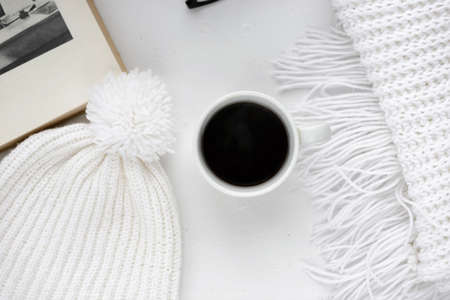 Handmade knitted wool scarf and cap. Winter clothes. Hot coffee cup on wooden background. Concept cozy atmosphere with a cup of coffee in winter. Top viewの写真素材